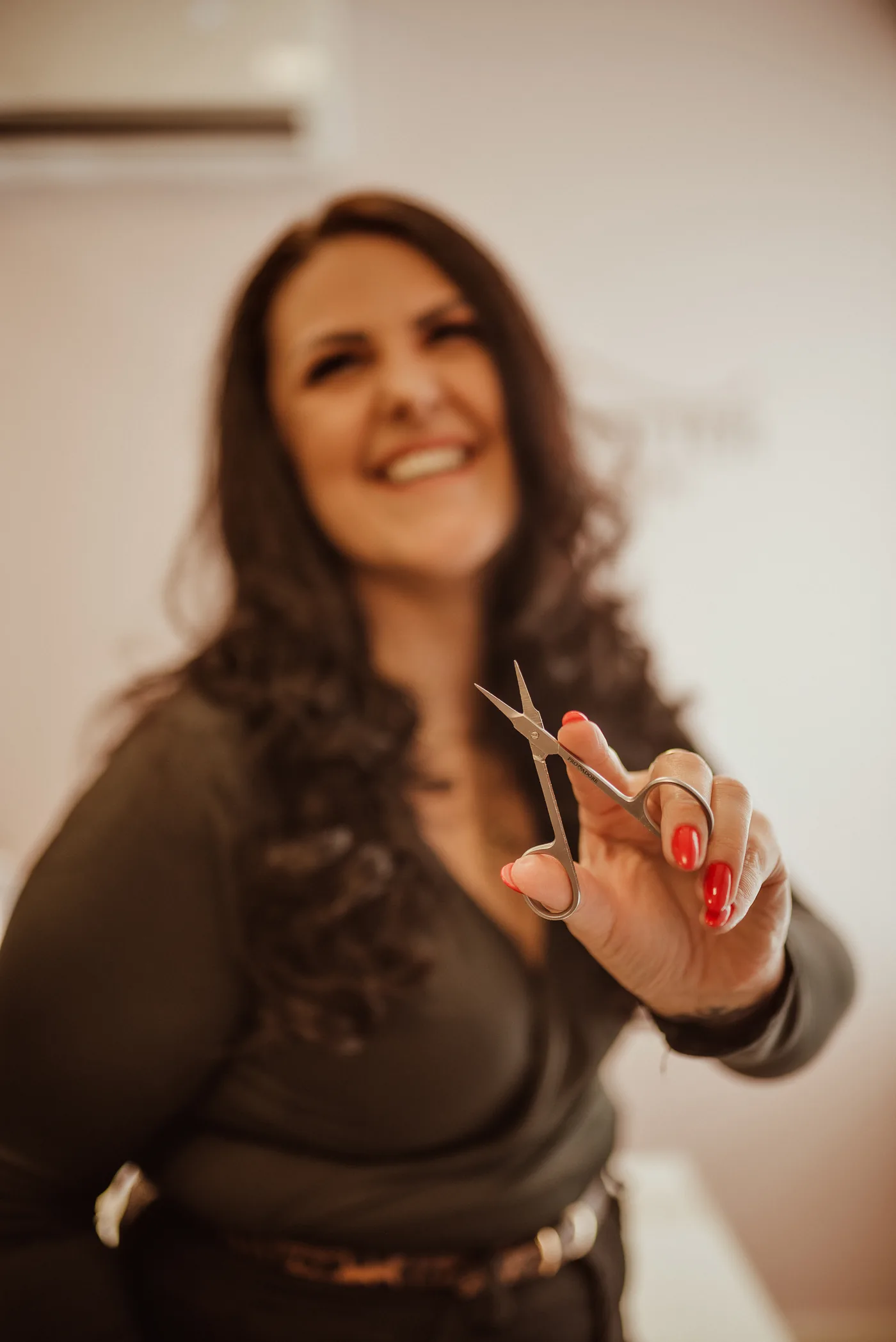 Roberta segurando um vidro de esmalte vermelho aberto, com o pincel à frente da câmera