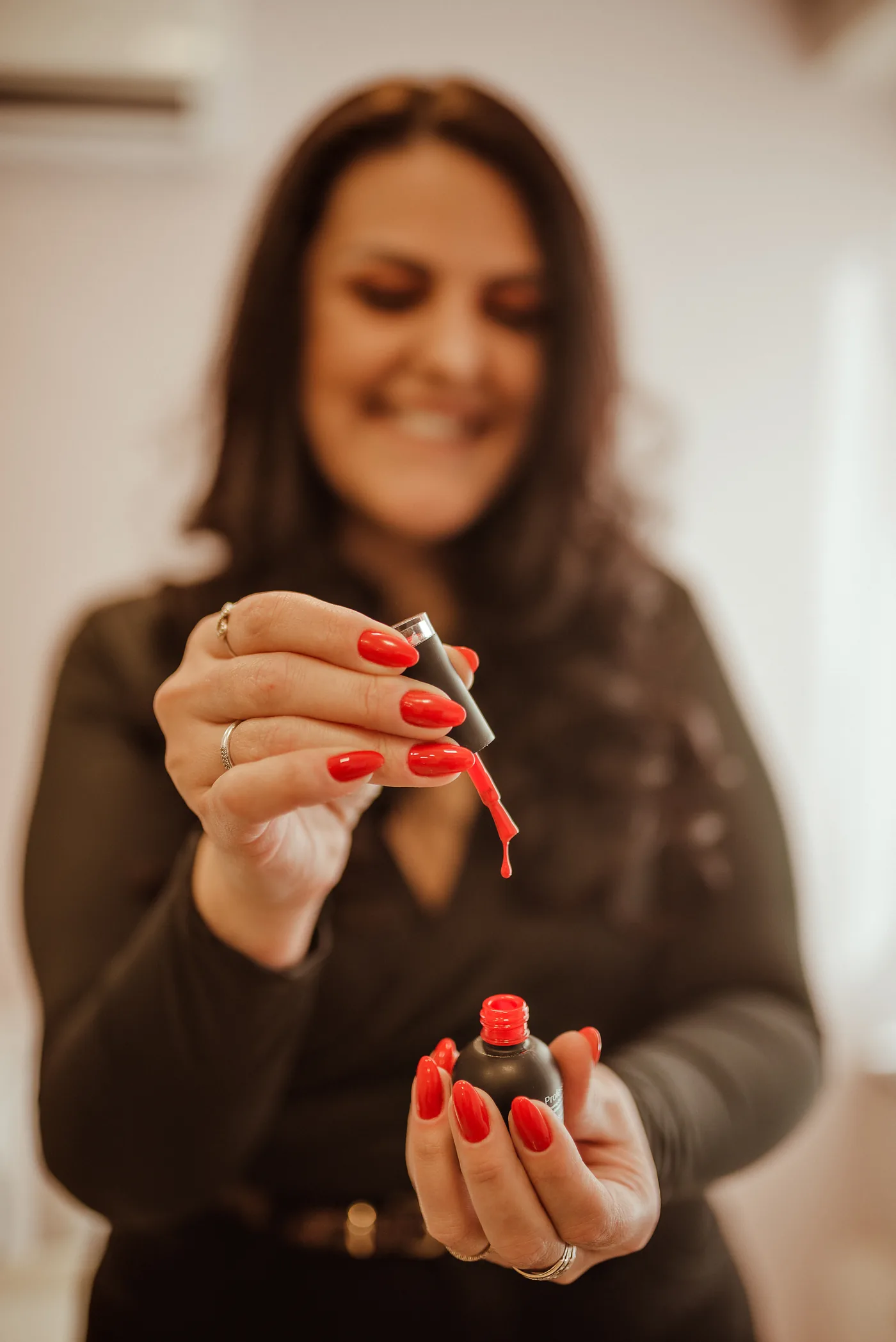 Roberta sorrindo enquanto segura uma tesourinha de cutícula em direção à câmera