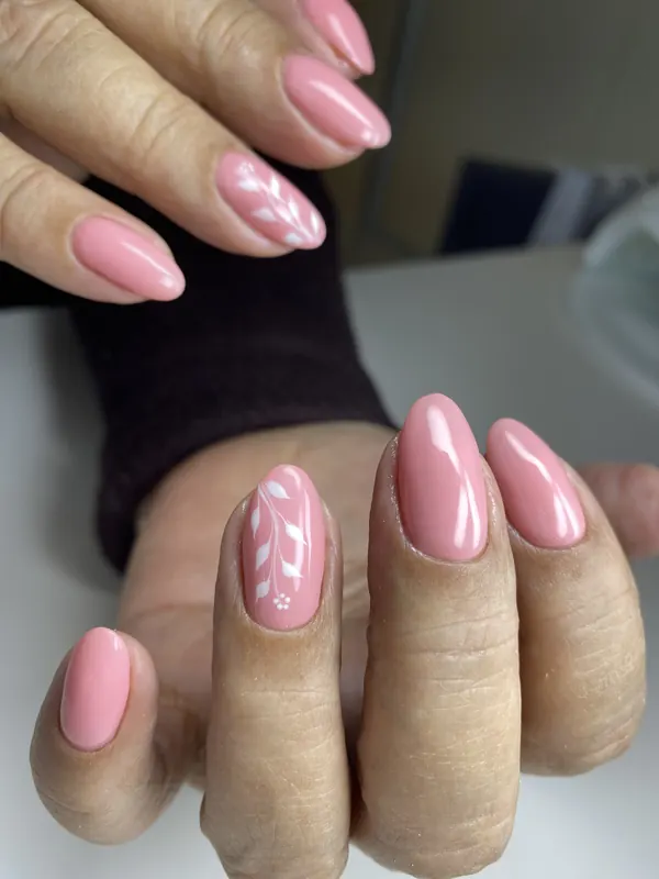 Unhas rosa com nail art de folhagem branca na unha anelar
